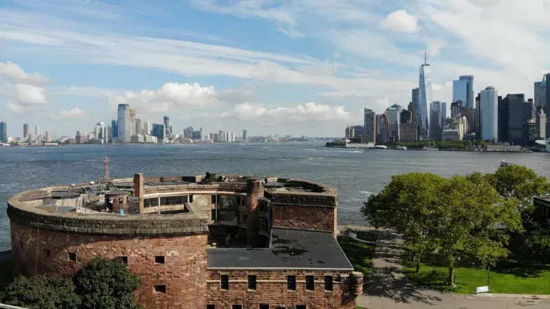 Castle Williams,  a circular fortification of red sandstone, in Governors Island, view of Manhattan in the background